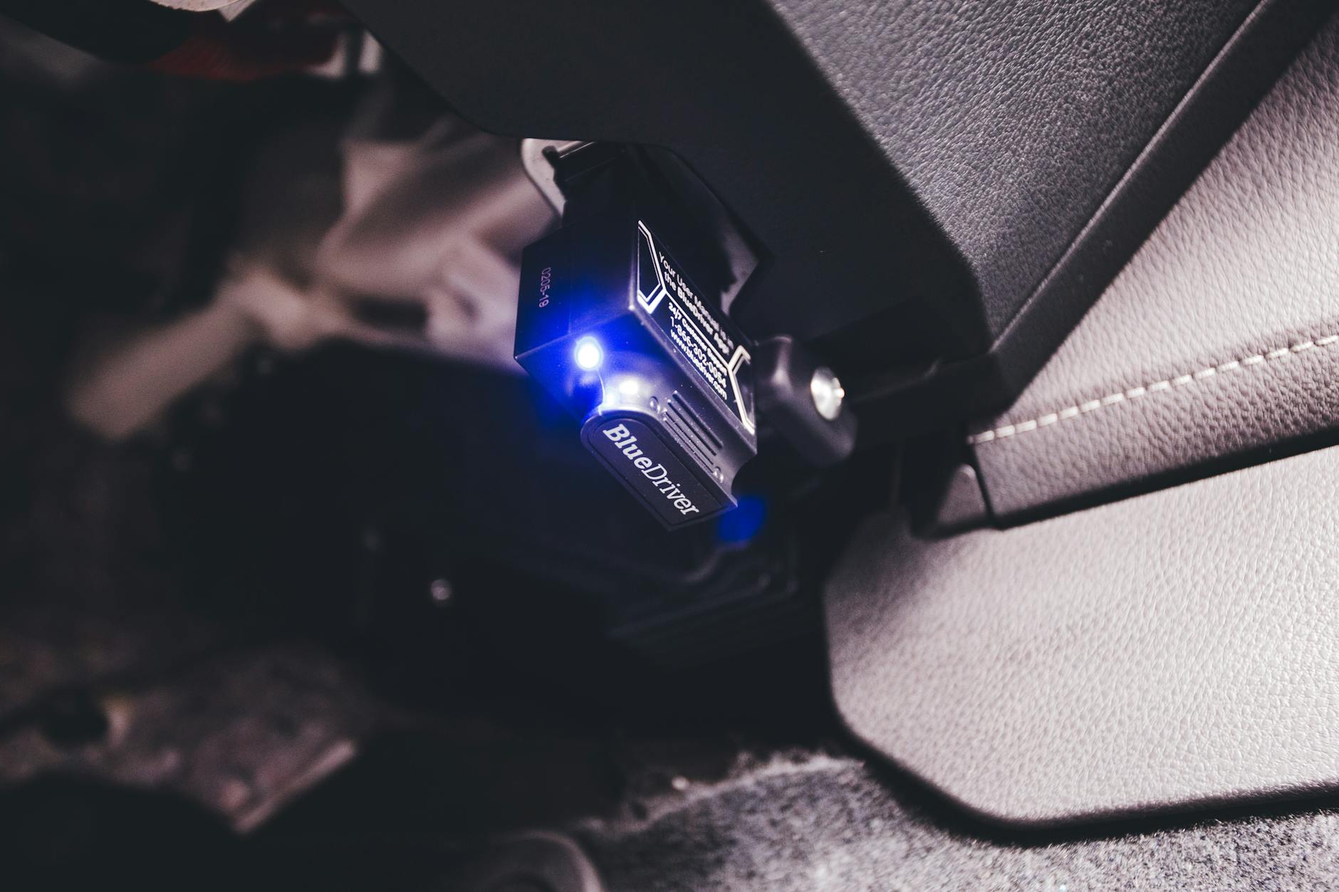 Samodzielna diagnostyka samochodu: jaki interfejs OBD wybrać, jak korzystać z aplikacji i interpretować kody błędów Interfejs Bluetooth OBD podłączony w aucie w niebieskim świetle